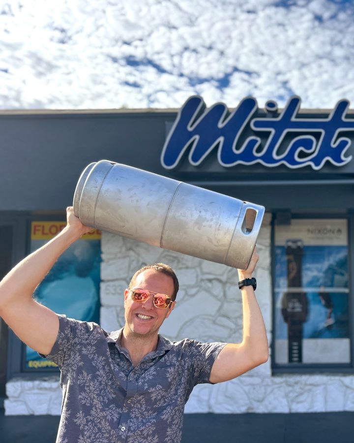 A Perpetual founder hoisting a Superfood Company Pineapple Ginger Kombucha keg outside Mitch's Surf Shop in La Jolla