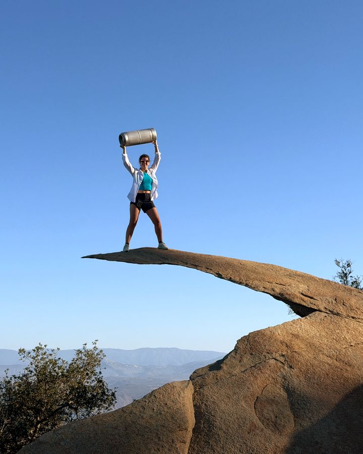 A Perpetual founder holding an AleSmith .394 Pale Ale keg overhead at the edge of Potato Chip Rock in Poway