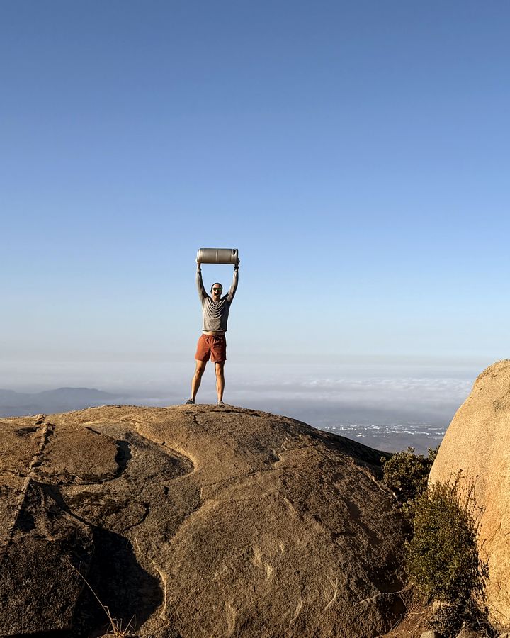 A Perpetual founder lifting a Superfood Company Real Root Beer keg overhead on a hilltop in Scripps Ranch