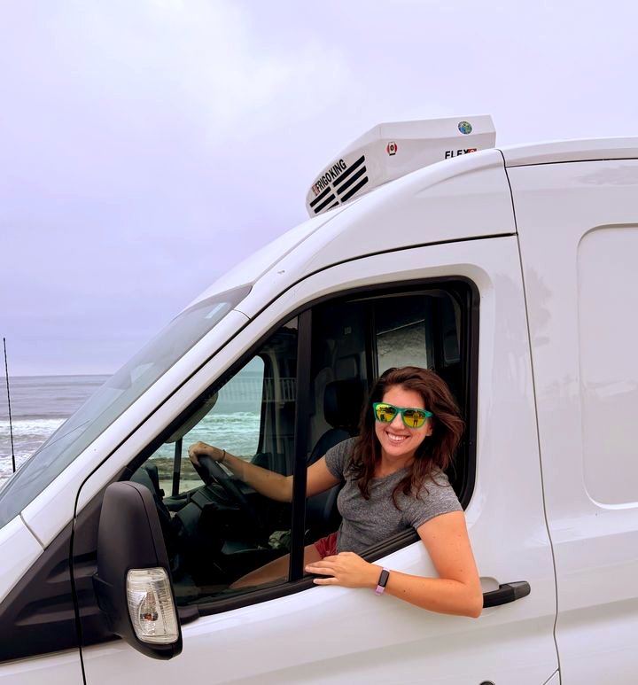 A Perpetual founder smiling in the cab of a refrigerated delivery van by the coast
