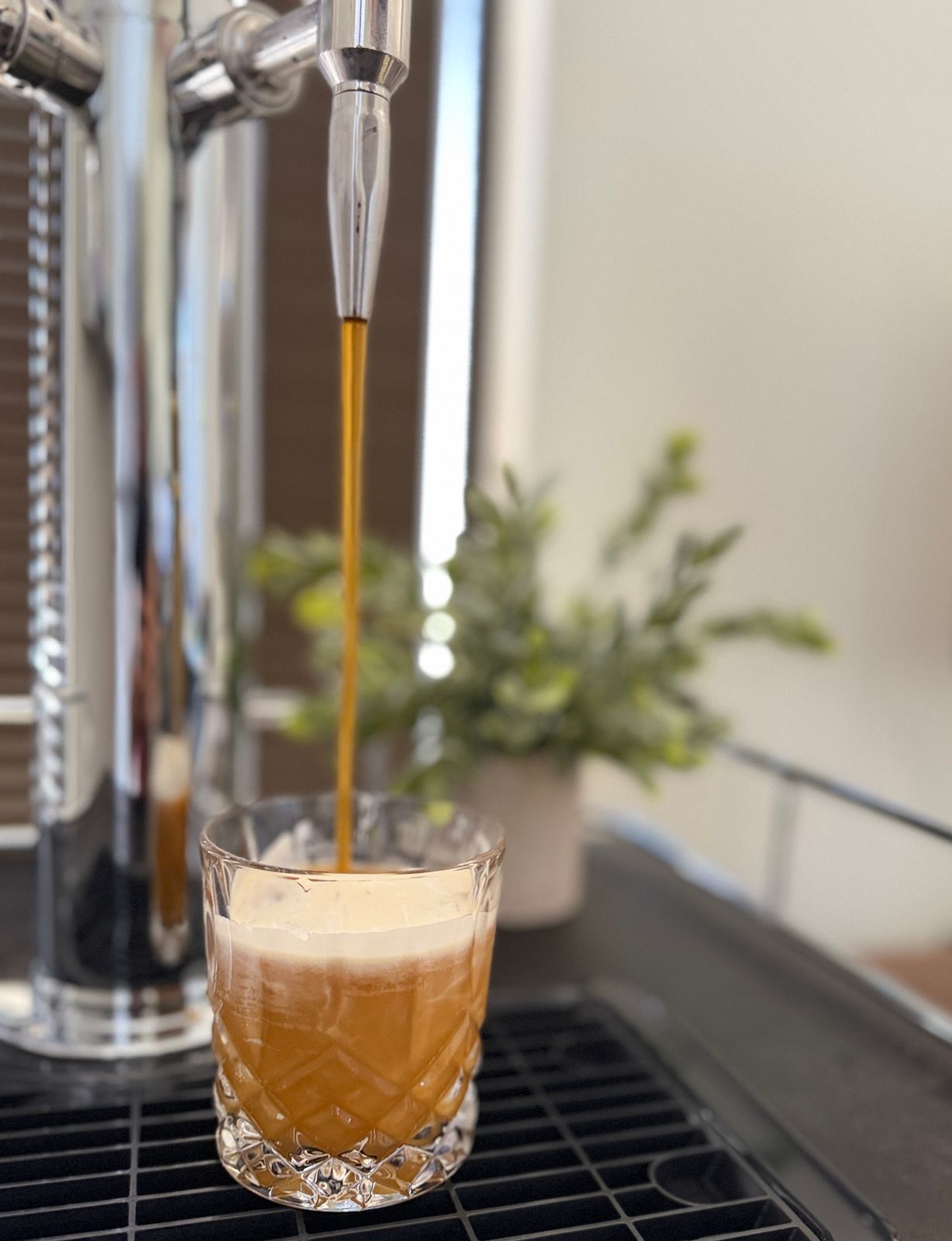 Nitro cold brew pouring from a Perpetual tap faucet into a crystal glass